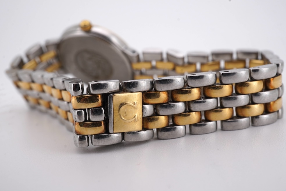 A lady's steel and gold plated Omega de Ville quartz wrist watch, with baton and quarterly Roman numerals, on a stainless steel and gold plated bracelet, case diameter 24mm, no box or papers. Condition - poor to fair